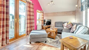 Ein Wohnzimmer mit einer Couch, einem Hocker, einem Couchtisch und einem Fernseher.