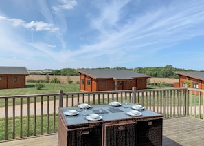 Una terraza de madera con una mesa lista para comer, con vista a una hilera de cabañas.