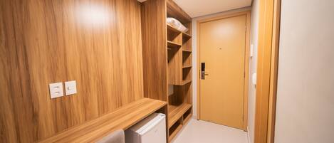 A compact room with wooden paneling, a built-in desk, a white radiator, and a door leading to another room.