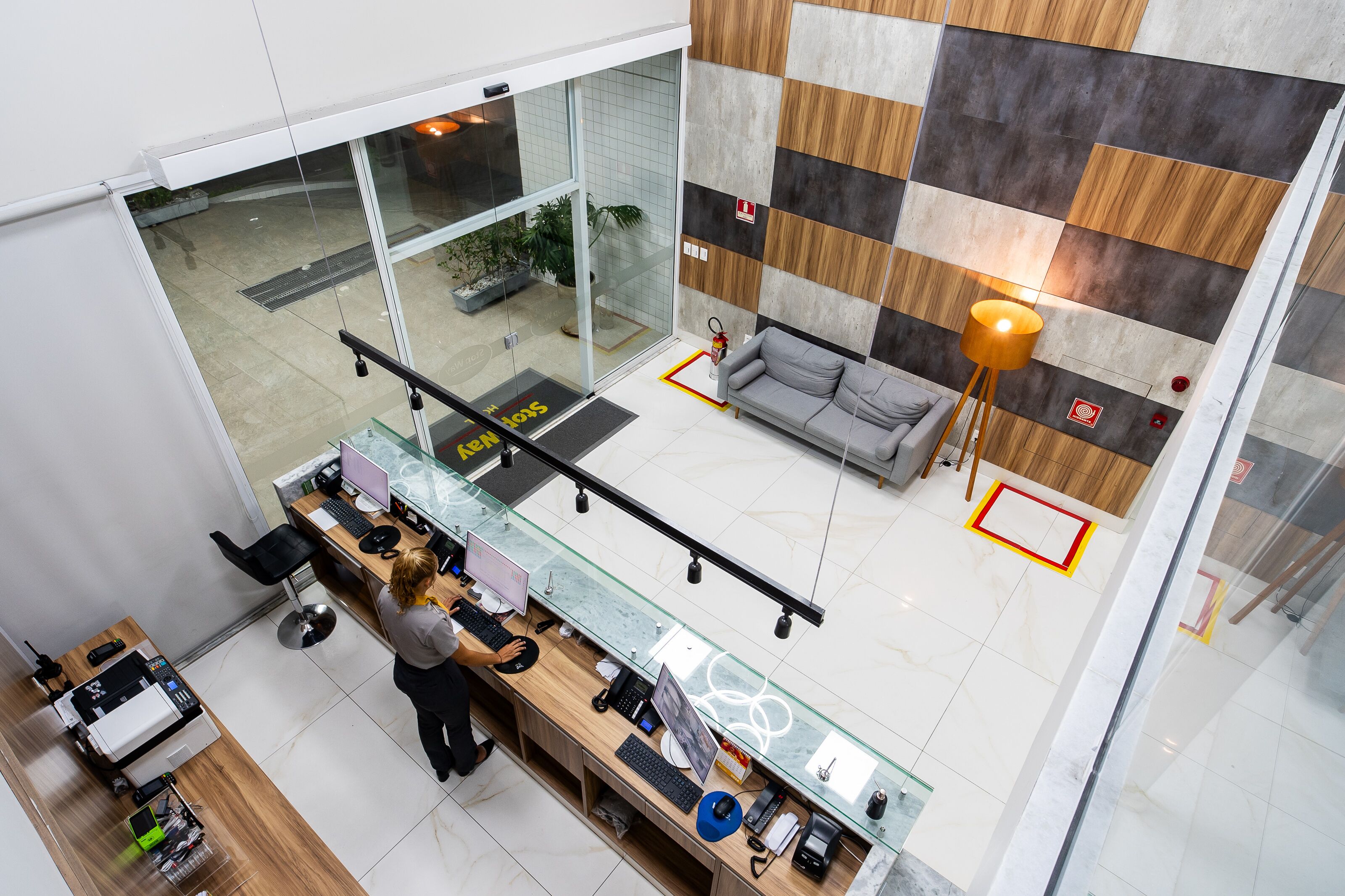 A modern office space with a glass desk, computer, and a sofa.
