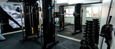 Een sportschool met diverse fitnessapparaten, waaronder een squatrek en halterbanken.