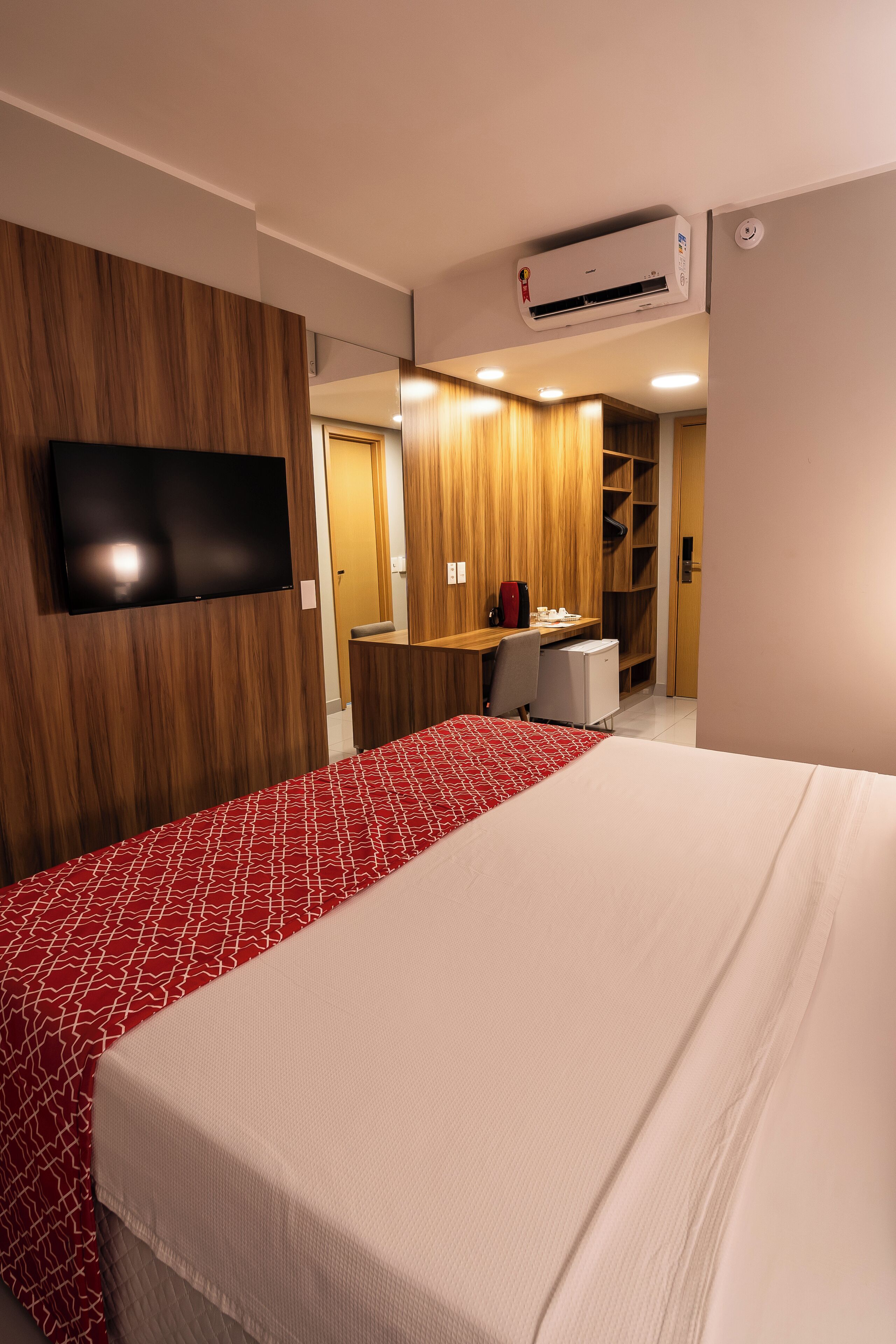 Une chambre d’hôtel équipée d’un lit, d’un bureau, d’une chaise, d’une télévision et d’un appareil de climatisation.