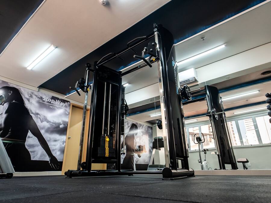 Un gimnasio con equipamiento de ejercicio, un espejo grande y un cartel de una persona haciendo ejercicio.