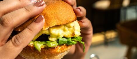 A person holding a burger with visible lettuce and cheese.