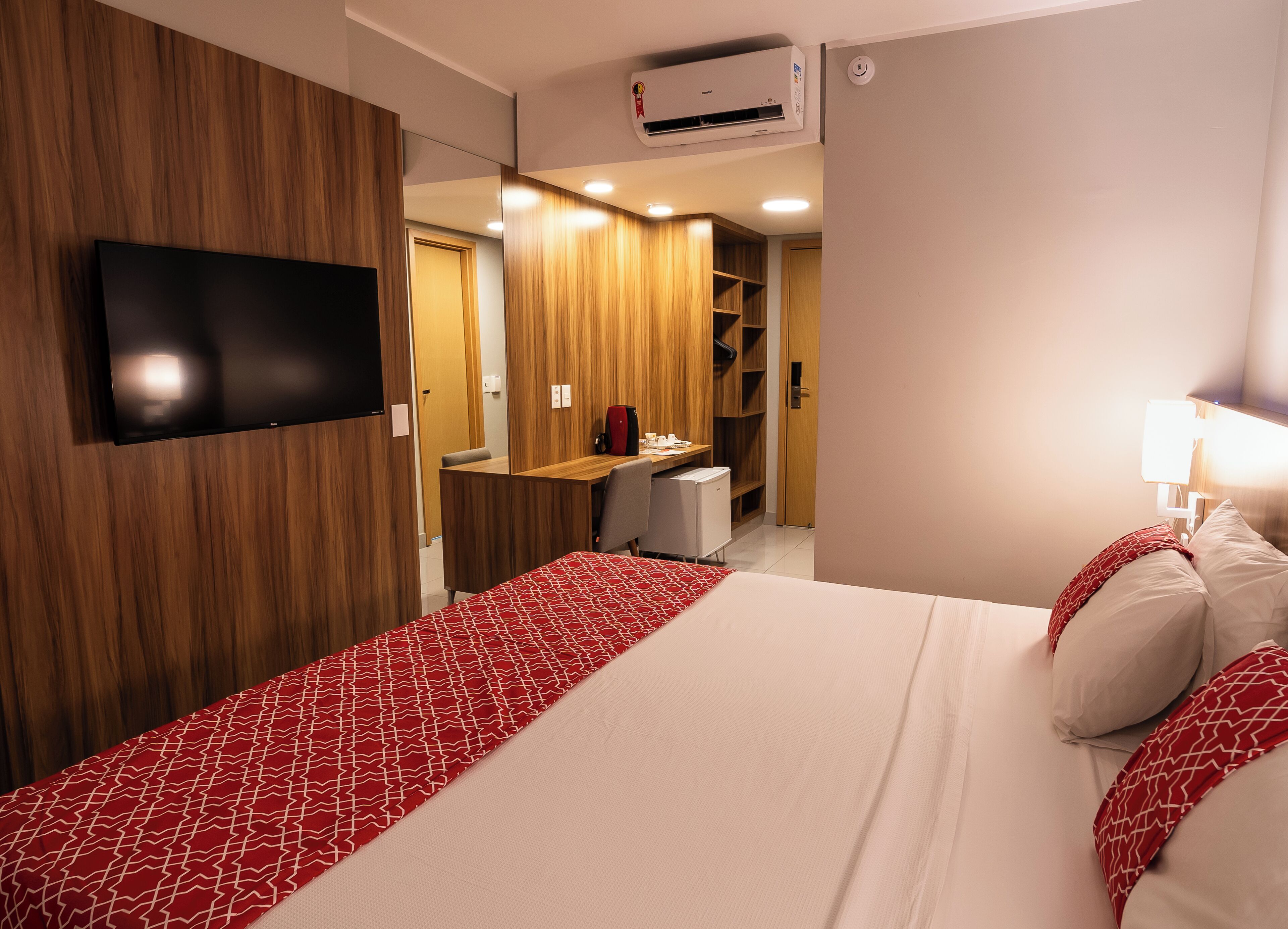 A hotel room with a bed, a desk, a chair, a television, and a wardrobe.