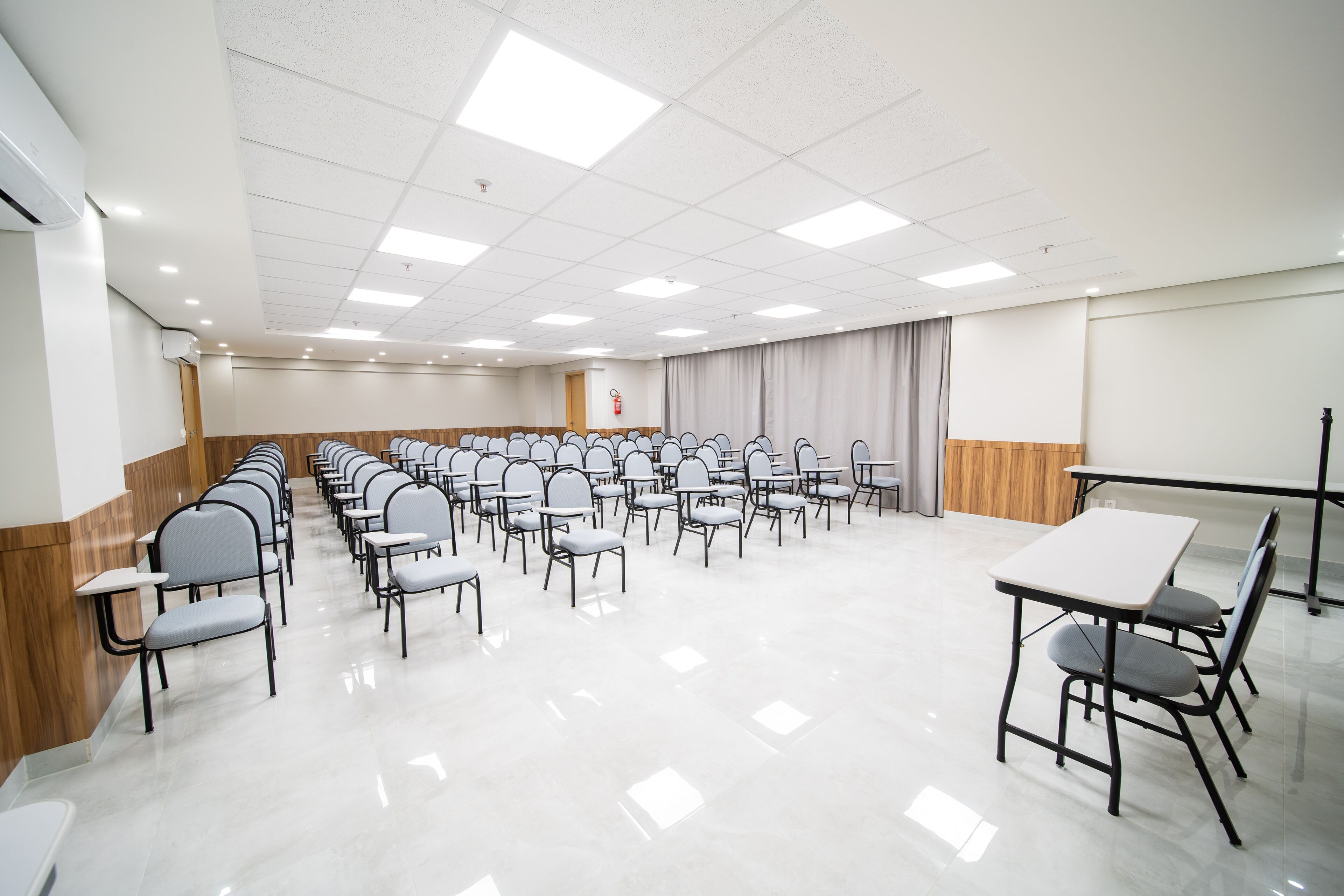 A conference room with rows of chairs and tables, a whiteboard, and a fire extinguisher.