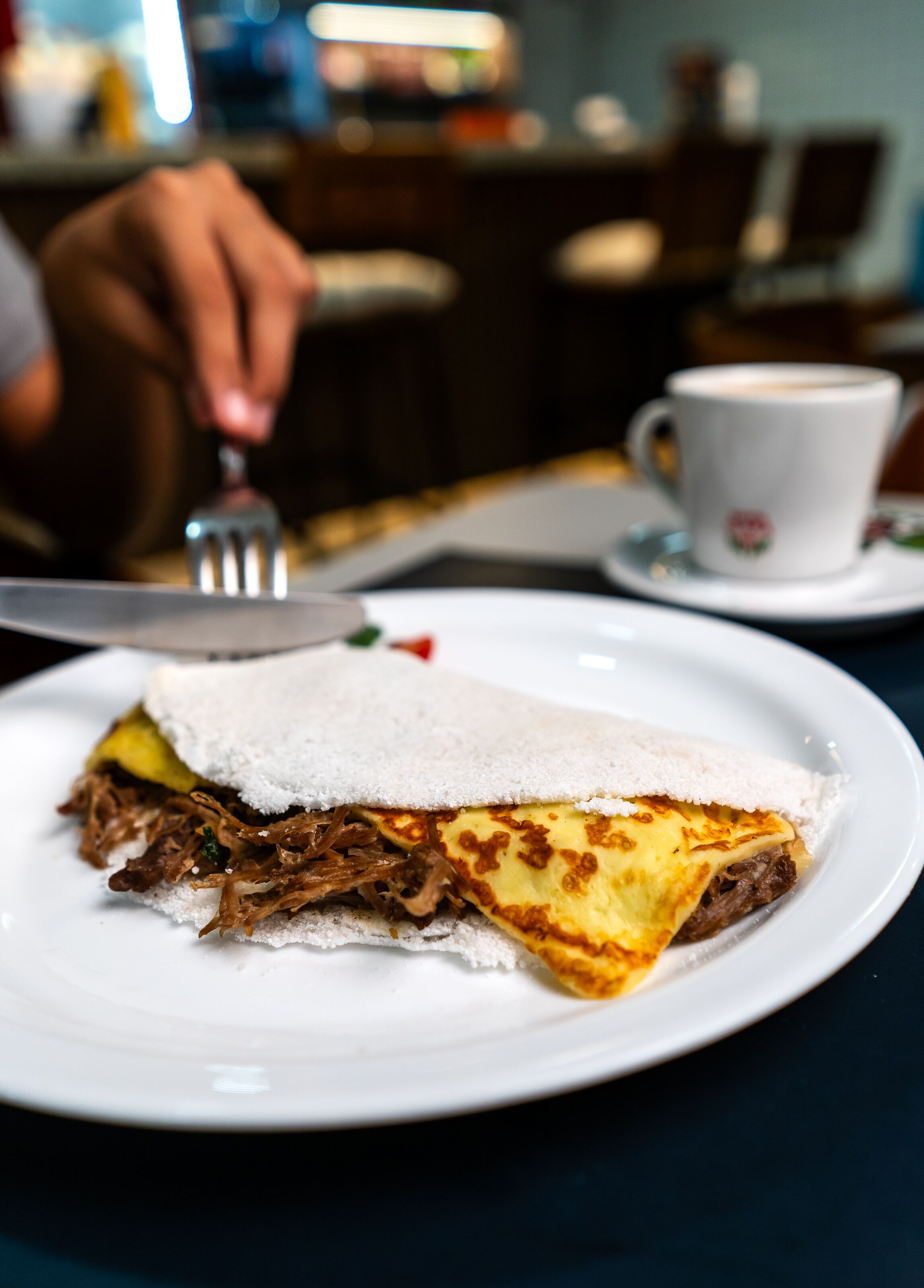 A plate with a sandwich and a cup of coffee on a table.