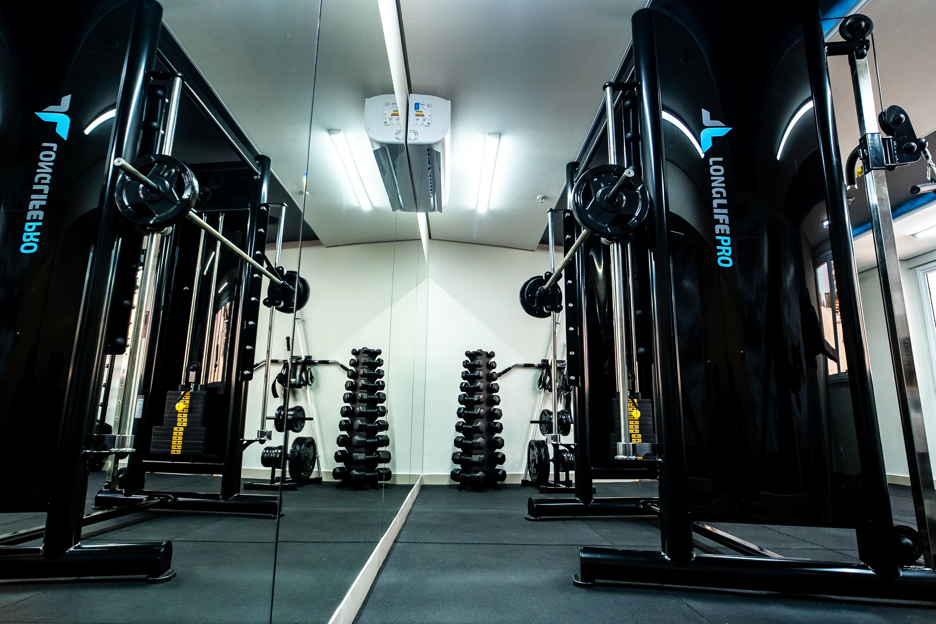 Uma academia com equipamentos de musculação, incluindo halteres e anilhas.
