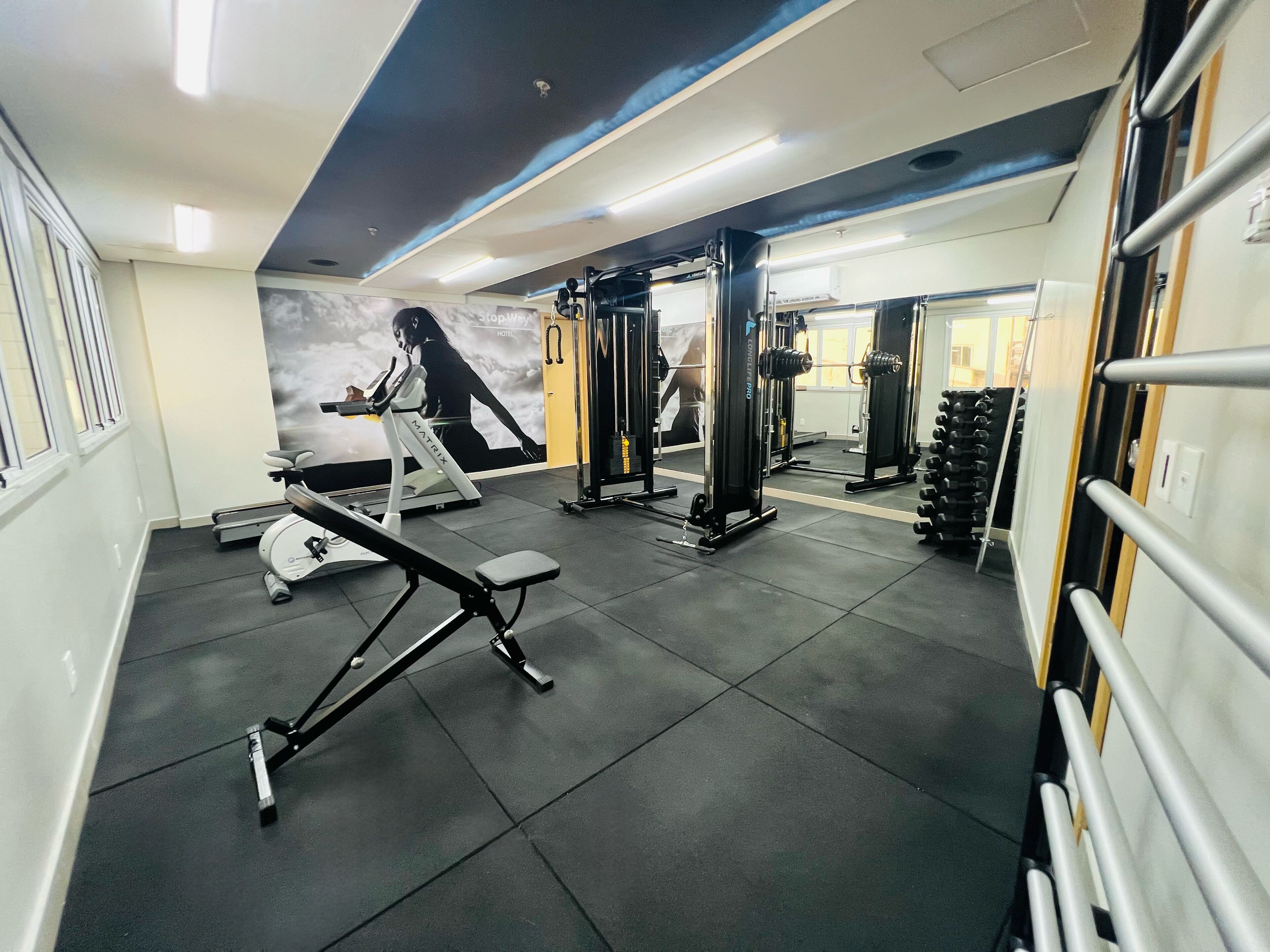 A gym with various exercise equipment, including a bench press, squat rack, and dumbbells.
