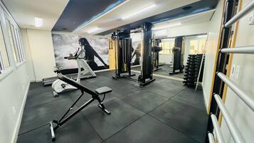 A gym with various exercise equipment, including a bench press, squat rack, and dumbbells.