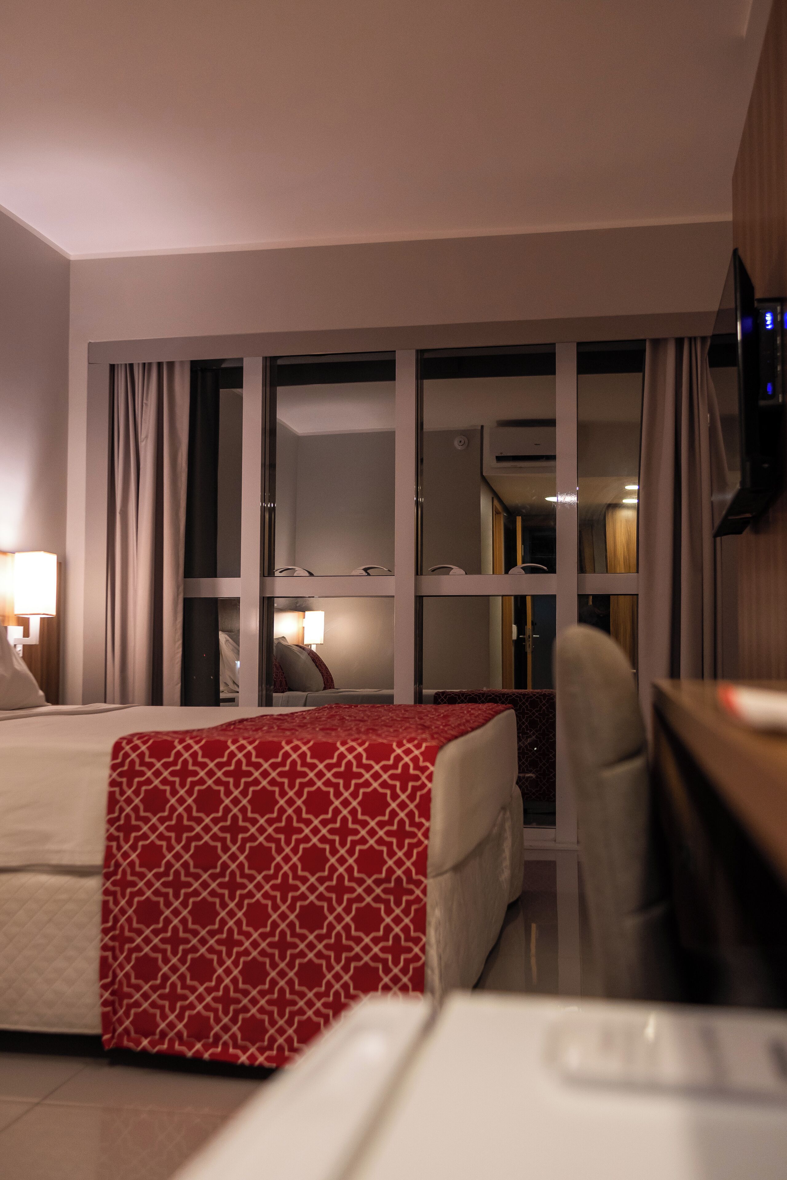 Une chambre d’hôtel avec un lit, un bureau, une chaise et un téléviseur.