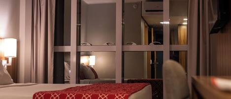 Habitación de hotel con cama, escritorio, silla y televisión.