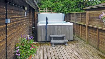 Une terrasse en bois avec un jacuzzi, une clôture en bois et un pot de fleurs.