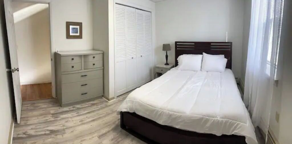 Une chambre à coucher avec un lit, une table de chevet, une commode et un placard.