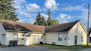 A two-story building with a sloped roof, a front porch, and a garage.