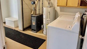 A laundry room with a washing machine, a dryer, a water heater, and a utility cabinet.