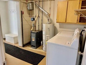 Une buanderie équipée d’un lave-linge, d’un sèche-linge, d’un chauffe-eau et d’un meuble de rangement pour les produits d’entretien.