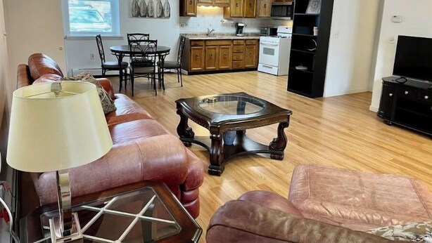 A living room with a leather sofa, a glass coffee table, and a TV stand.
