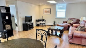 A living room with a round table, a sofa, a TV, and a bookshelf.