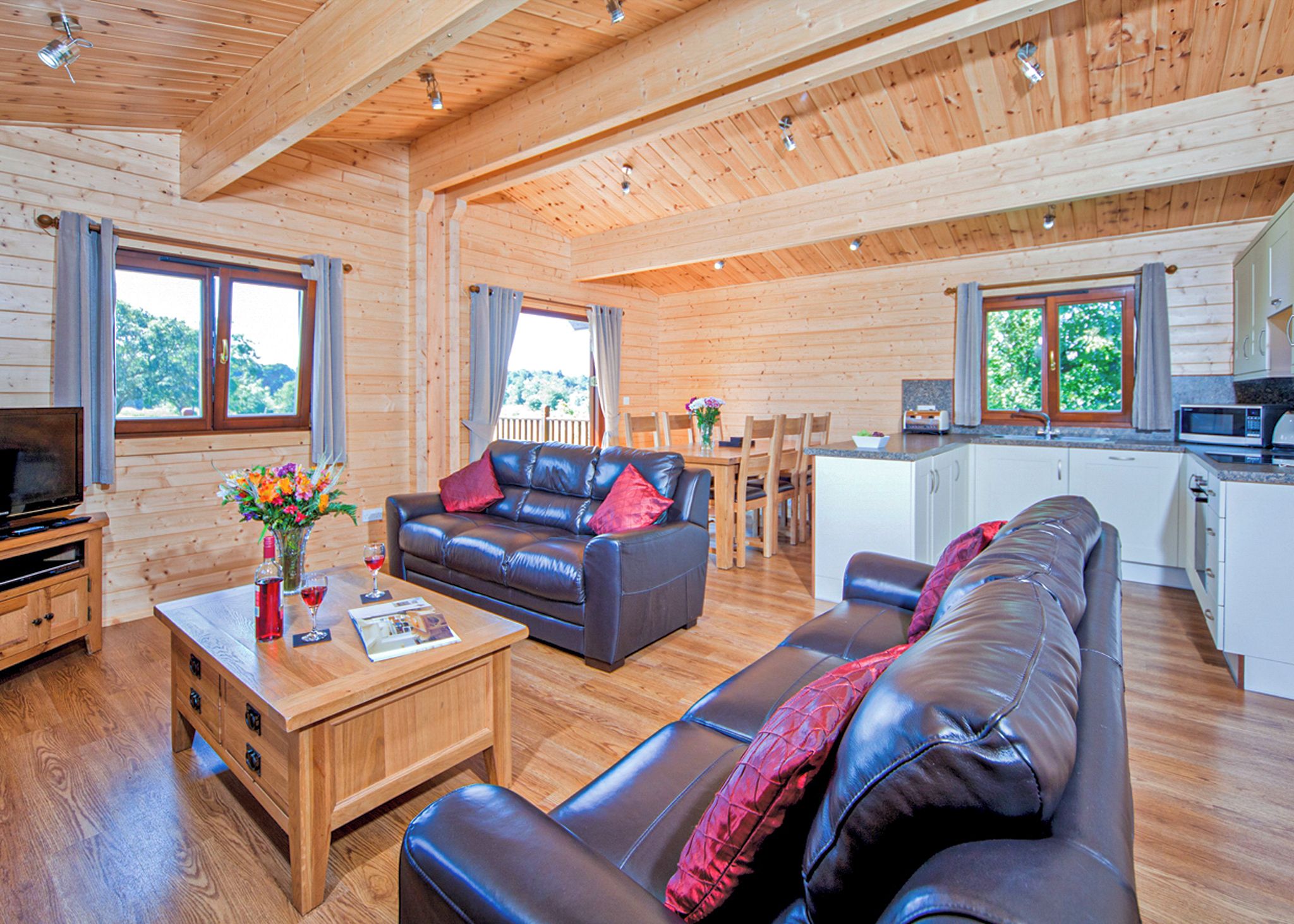 A wooden cabin interior with a living room, dining area, and kitchenette.