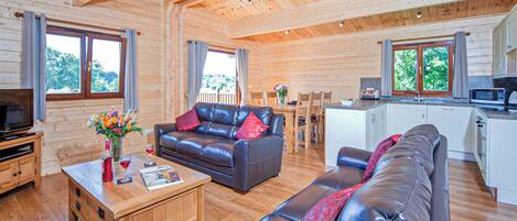 A wooden cabin interior with a living room, dining area, and kitchenette.
