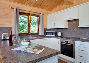 A modern kitchen with granite countertops, white cabinetry, a built-in microwave, and a black oven.