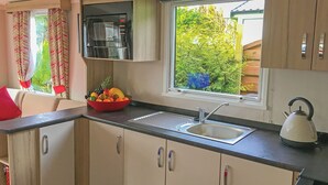 A compact kitchenette with a sink, a kettle, and a bowl of fruit on the counter.