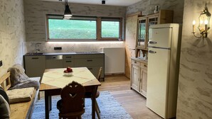 Una cucina compatta con zona pranzo, frigorifero e finestra con vista sul verde.