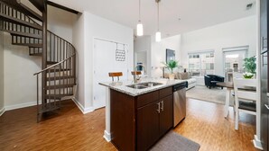 A modern kitchen with a central island, a built-in dishwasher, and a wooden staircase. - 3 Bedroom Centrally Located (Columbus)