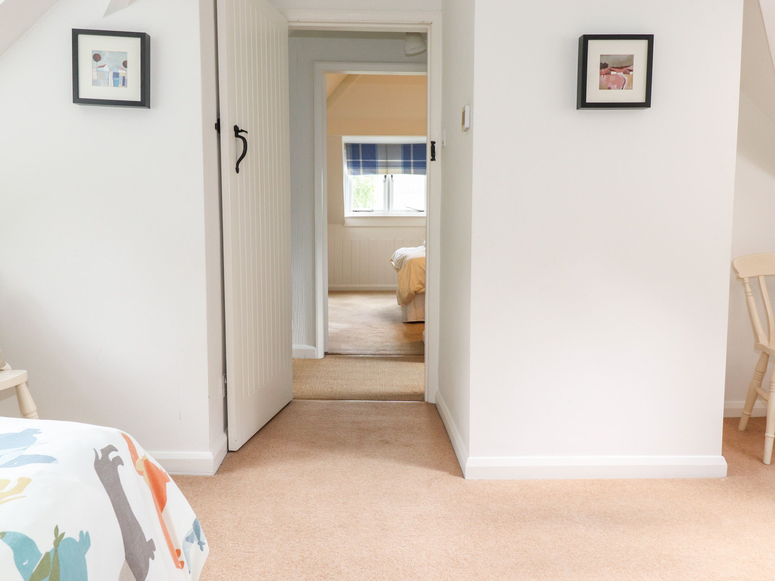 A bedroom with a bed, a chair, and a door leading to another room.