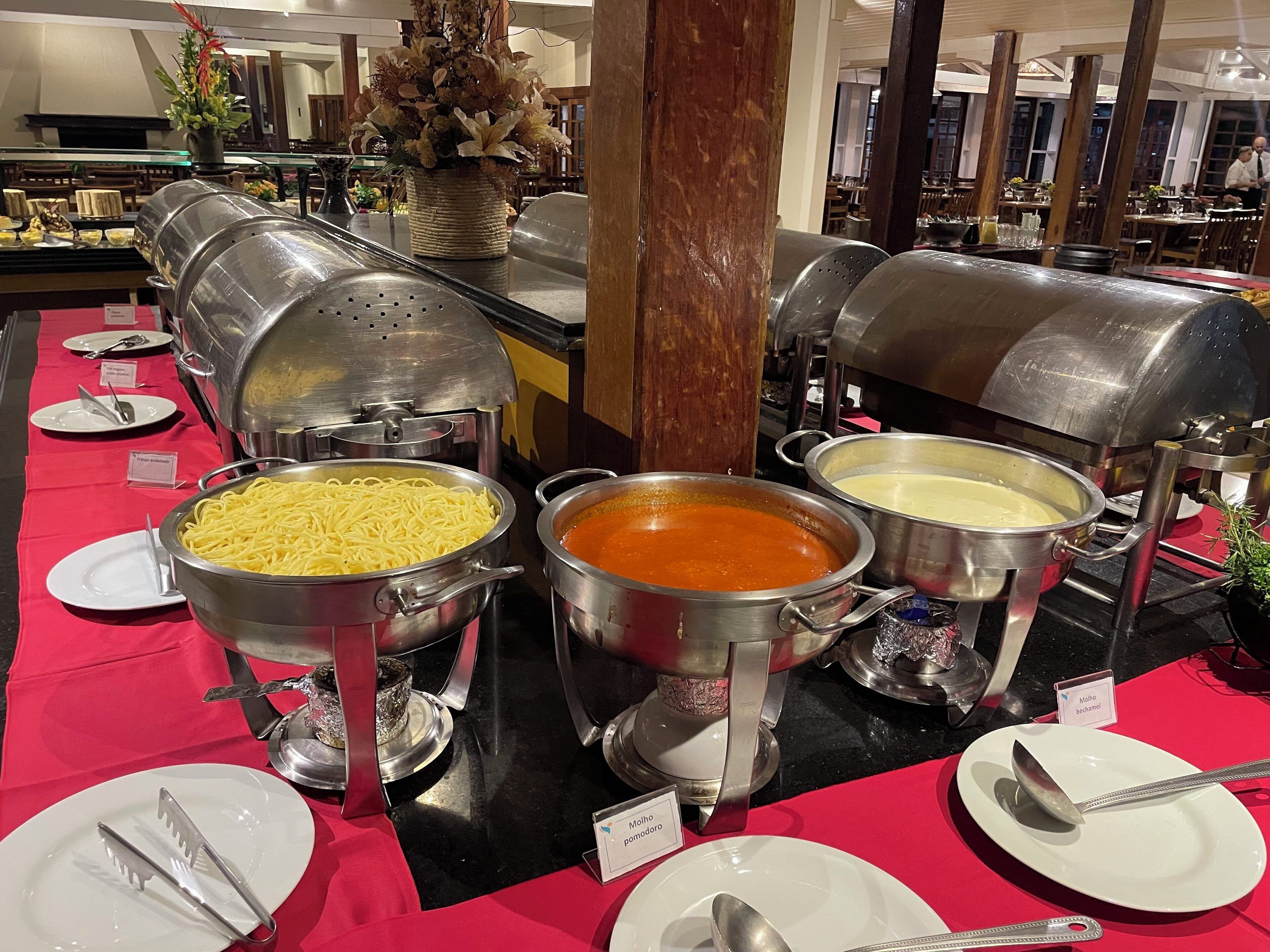A buffet setup with multiple food stations, including pasta, soup, and a dessert.