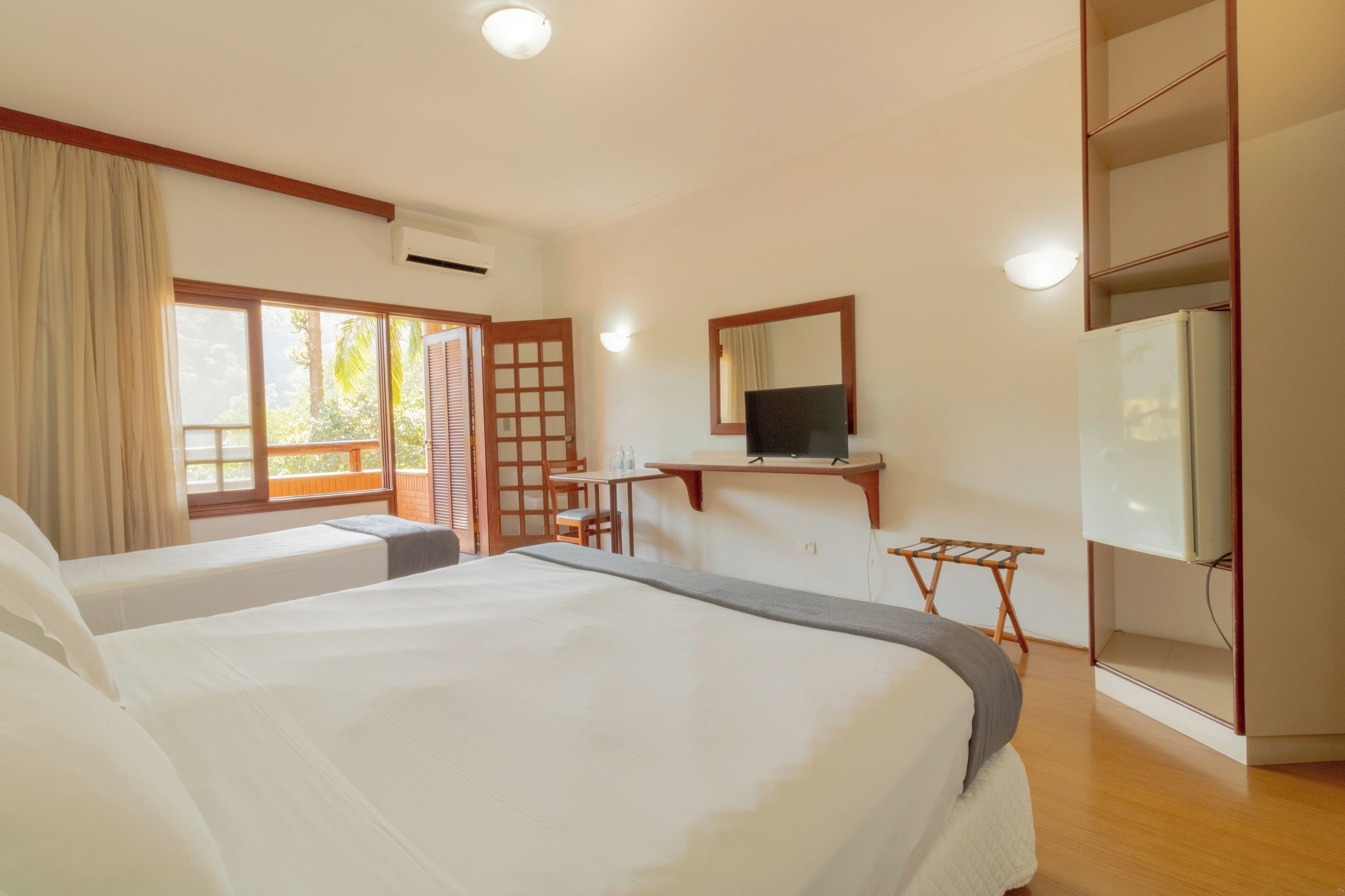A hotel room with two beds, a desk, a TV, and a wardrobe.