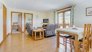 A spacious living area with a sofa, a TV, and a dining table with chairs. - Valley View Lodge Pet (Penybont, Llandrindod Wells)