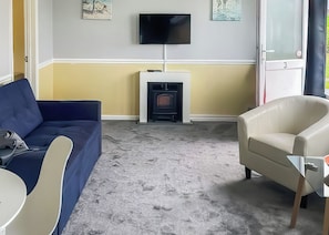 A living room with a blue sofa, beige armchair, and a fireplace.