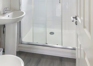 A bathroom with a white sink, a glass shower enclosure, and a white toilet.