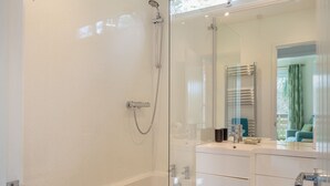 A modern bathroom with a glass shower enclosure, a bathtub, and a vanity with a mirror. - Comfortable log cabin offering self-catering in the heart of Cornwall. (Ruthernbridge, Nr Bodmin)