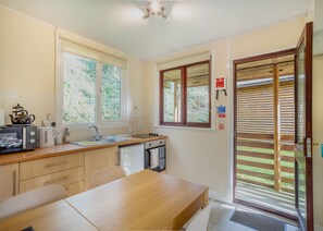 A compact kitchen with a dining area, a microwave, a kettle, and a sink. - Comfortable log cabin offering self-catering in the heart of Cornwall. (Ruthernbridge, Nr Bodmin)
