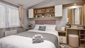 Un dormitorio con cama, mesitas de noche, tocador con espejo y estanterías integradas.