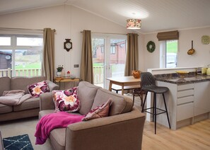 A cozy living room with a sofa, a dining table, and a kitchen area with a bar stool.