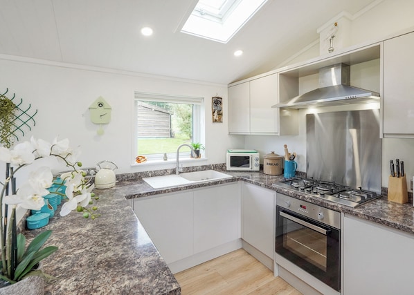 A modern kitchen with a built-in oven, microwave, and stainless steel range hood. - 3 bedroom accommodation in Kielder (Kielder)