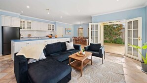 Un espace de vie moderne comprenant une cuisine, un coin repas et une grande porte-fenêtre coulissante donnant sur un jardin.