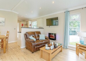 Una sala de estar acogedora con un sofá de cuero, una mesa de centro de madera y un televisor montado en la pared.