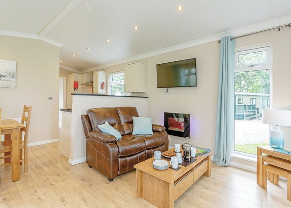 A cozy living room with a leather sofa, wooden coffee table, and a TV mounted on the wall.