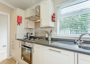 Eine moderne Küche mit Edelstahlgeräten, einem Fenster mit Jalousien und einem an der Wand befestigten Feuerlöscher.