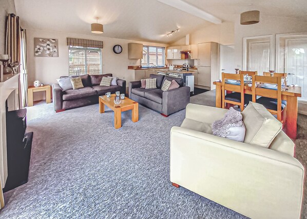 A living room with two sofas, a coffee table, and a dining area with a table set for four.