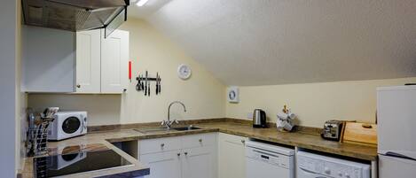 A compact kitchen with a microwave, sink, dishwasher, and a small refrigerator.
