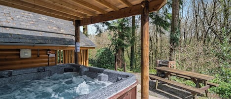 En træhytte med jacuzzi, et picnicbord og en sti af sten.