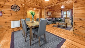 Et interiør af en træhytte med spiseområde, sofa og pejs.