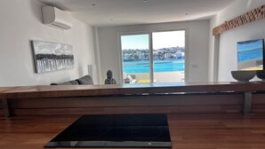 A modern kitchen with a wooden countertop, a built-in stove, and a view of a pool and buildings. - Santa Ponsa Mallorca first line of sea - Aparthotel (Santa Ponça)