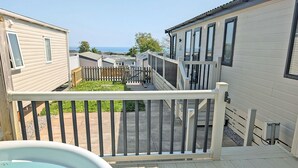 Eine Terrasse mit Whirlpool, Holzgeländern und Blick auf andere Blockhütten.